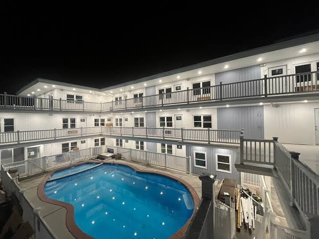 The courtyard pool lit up at night with the building's balconies behind it